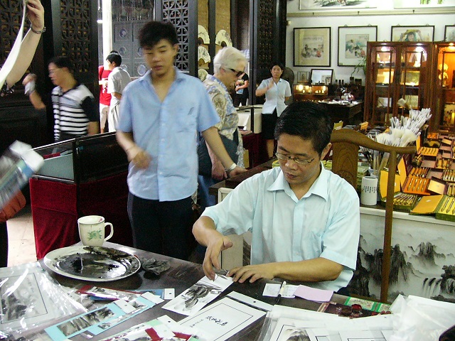 A man doing hand paintings. He dipped the side of his hand in the paint and dabbed it on the paper. Some of his paintings were amazing