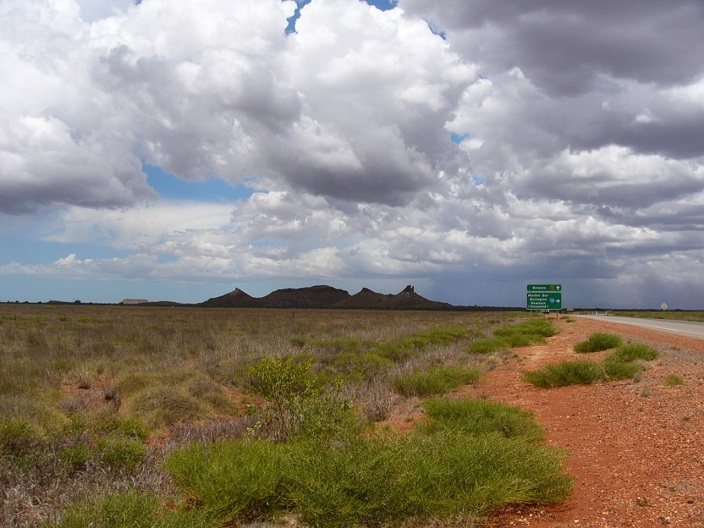 Stormy clouds over rock formation near road after Port Hedland