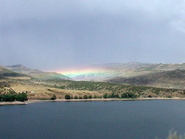 My granddaughter took this photo as I was driving across the reservoir in the rain with no place to pull over.  The far valley was fully illuminated by the rainbow, even though we were in the dark clouds.  It was an enlightening experience that I can relive whenever I see her photo. 